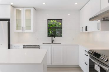 Bright modern white kitchen with sleek cabinets and stainless steel appliances.