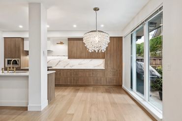 Modern kitchen and dining area with wood cabinetry and large sliding glass doors.