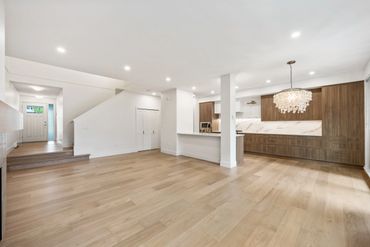 Spacious modern living area with light wood flooring and white walls.