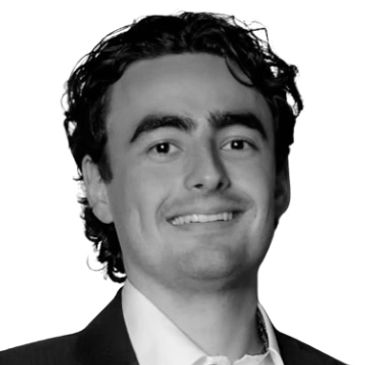 Young man in a suit smiling confidently against a white background.