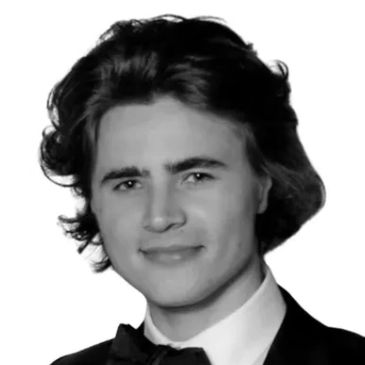 Young man in a tuxedo with a bow tie smiling.