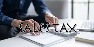 Person calculating sales tax with documents and calculator.