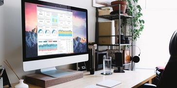 Modern workspace with a large monitor displaying financial charts and a tidy desk setup.