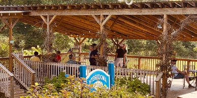 People relaxing under a wooden pavilion in a garden setting.