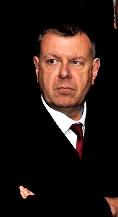 Serious man in a suit with a dark background.