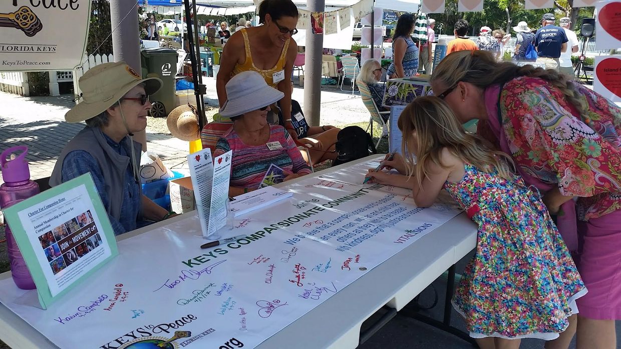 Keys to Peace women sitting at a booth with a little girl coloring