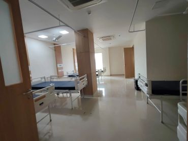 Empty hospital room with beds and chairs.