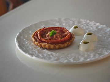 Tartelette aux tomates avec garniture blanche et pesto.