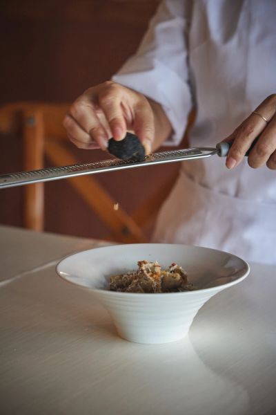 Un chef râpe un ingrédient noir sur un plat.