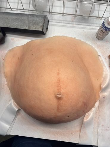 A realistic prosthetic belly with a navel and skin texture.