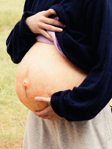 Close-up of a pregnant belly with hands gently holding it.