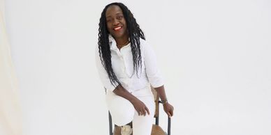 Femme souriante assise sur une chaise blanche.