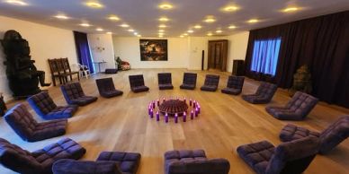 Une grande salle avec des coussins en cercle autour de bougies.