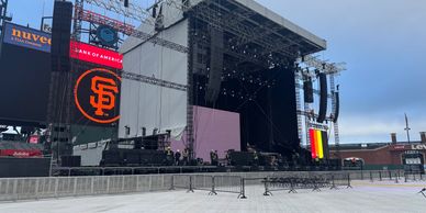 Empty outdoor concert stage with large screens and barriers.