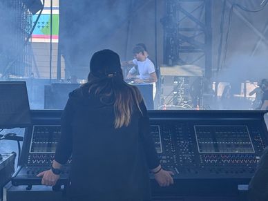 Person operating sound equipment at a concert stage.