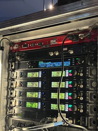 Professional audio equipment rack with multiple wireless receivers.