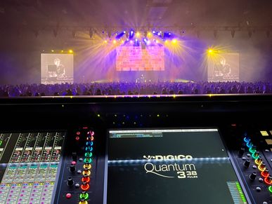 Concert stage with audio mixing console in foreground.