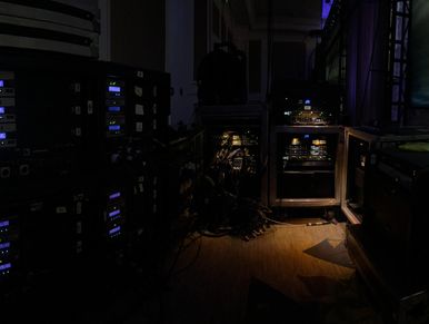 Dark backstage area with electronic equipment and cables.