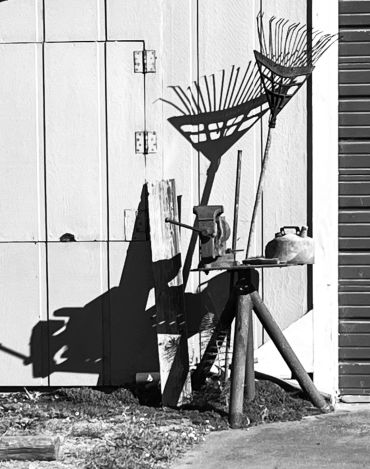 Shadow art of garden tools against a wall.