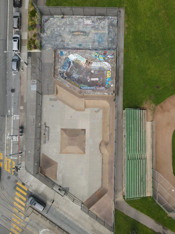 Aerial view of a skatepark next to a baseball field with bleachers.