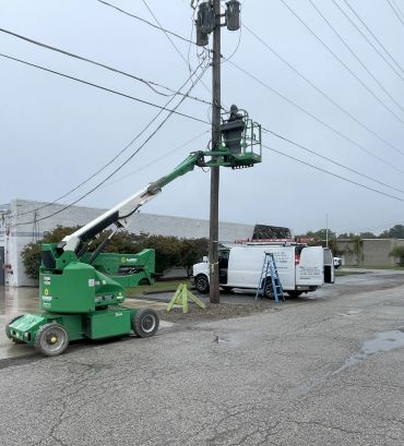 Worker on a lift repairing electrical lines on a utility pole.