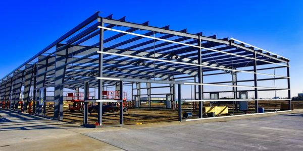 Steel framework of a large building under construction on a clear day.