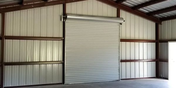 Empty metal garage interior with a closed roll-up door.