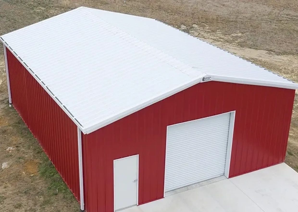 Red metal building with white roof and doors on a concrete base.