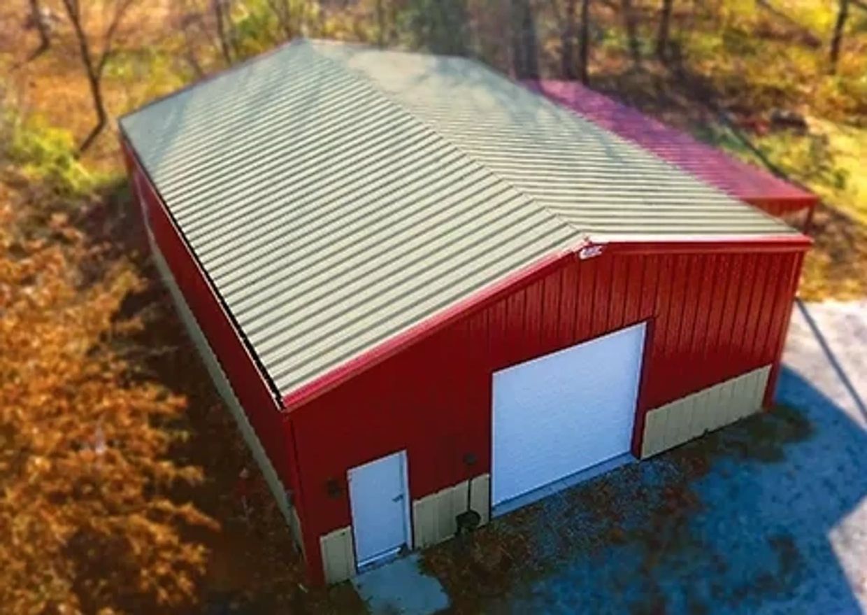 Red metal building with a large white garage door and side door.