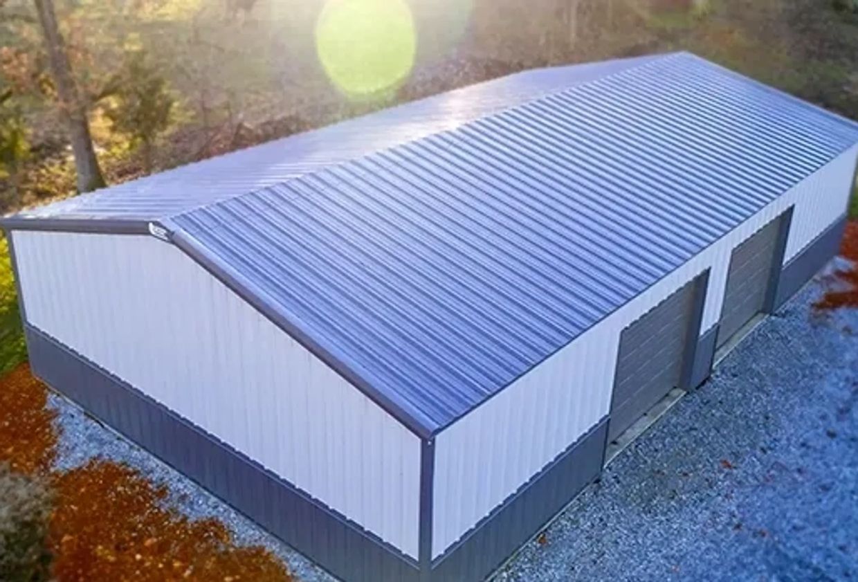 Large metal storage building with two garage doors in a wooded area.