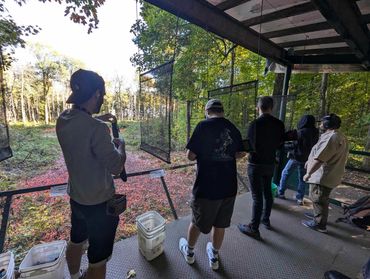 People watching through glass panels in a wooded area.