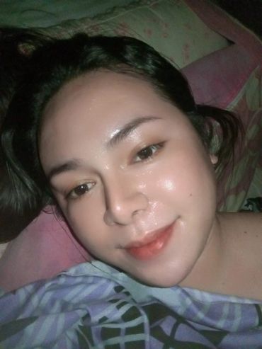 Close-up selfie of a person lying down with a gentle smile.