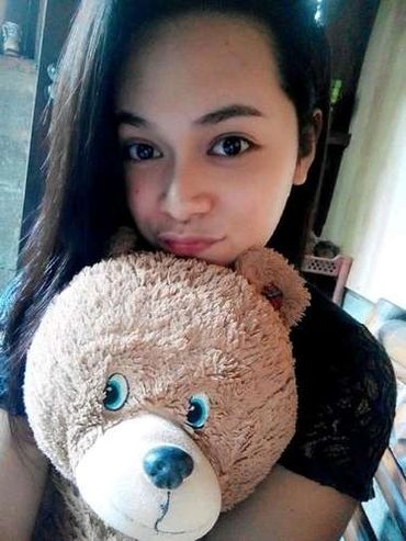 Young woman hugging a large teddy bear indoors.