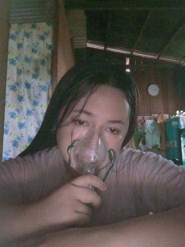 Person holding an oxygen mask to their face indoors.