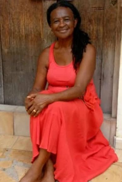 Woman in a red dress sitting and smiling.