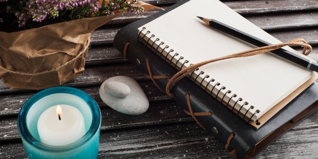 Journal laying on a table next to a relaxing candle and Lavender. Take notes during oracle reading,