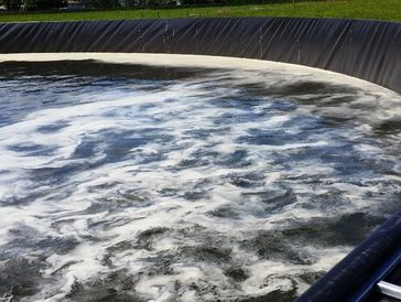 Circular water treatment tank with aeration and foam on the surface.