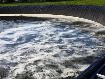 Circular water treatment tank with aeration and foam on the surface.