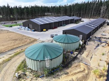 Large industrial tanks and warehouse buildings in a forested area.