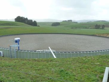 Large circular water reservoir in a green hilly landscape.