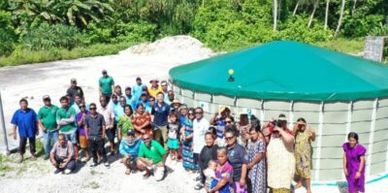 A large group of people gathered outdoors near a large circular water tank.