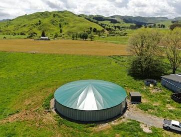 A large circular green-roofed water tank in a rural landscape.