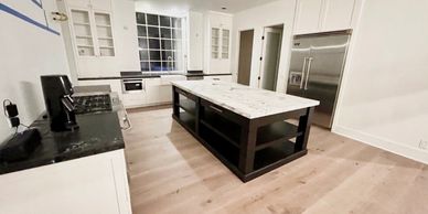 Modern kitchen with black and white design, large island, and wooden floor.