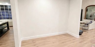 Empty white corner wall with wooden floor.