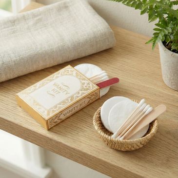 Vanity kit with cotton pads, swabs, and nail file on a wooden table.