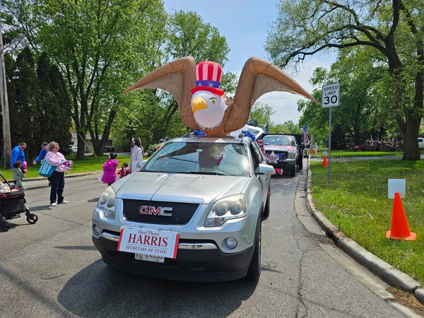 Parade vehicle with patriotic eagle decoration and campaign sign for Harris.
