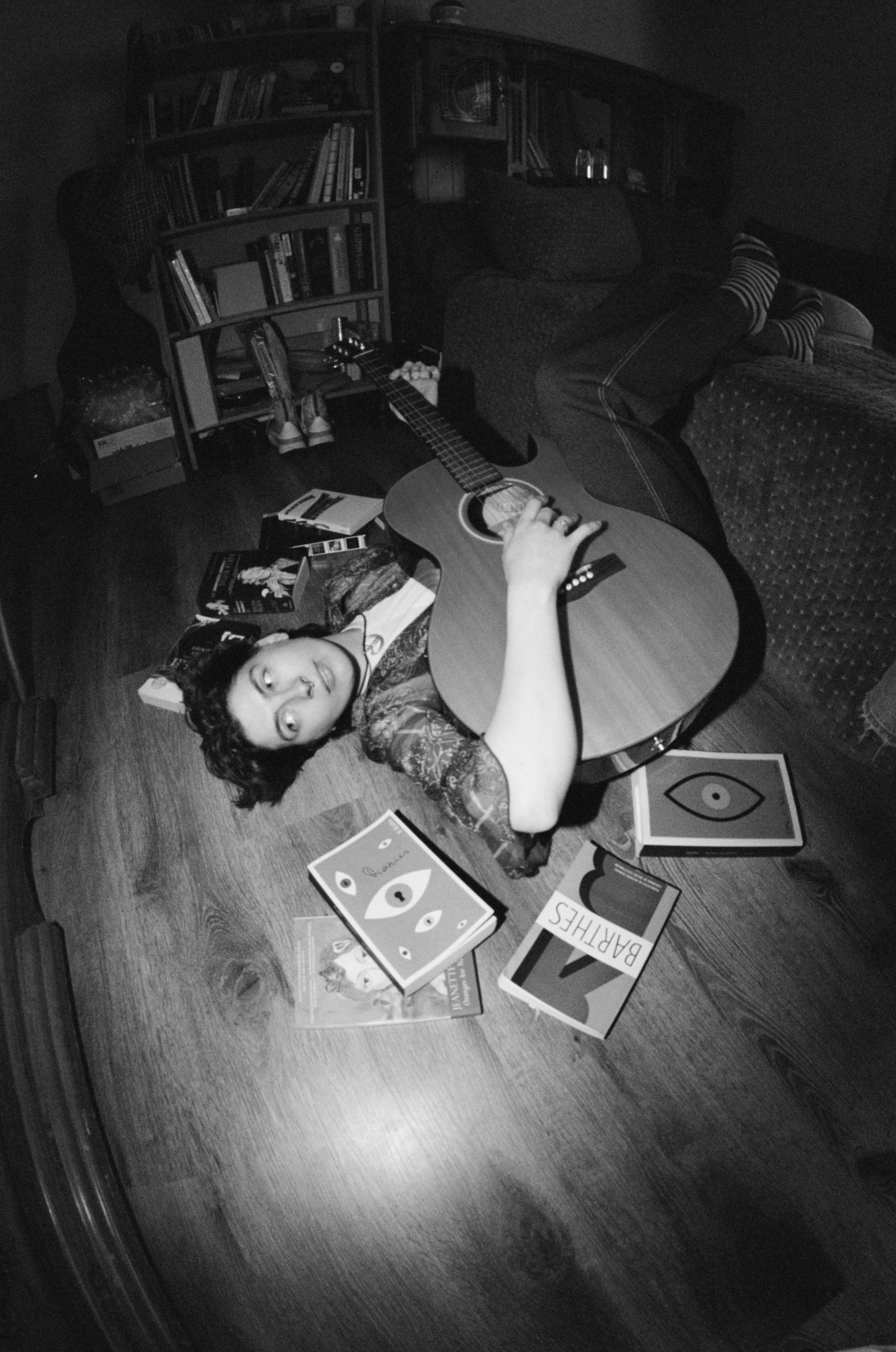 Blue laying on the ground wile holding a guitar. 