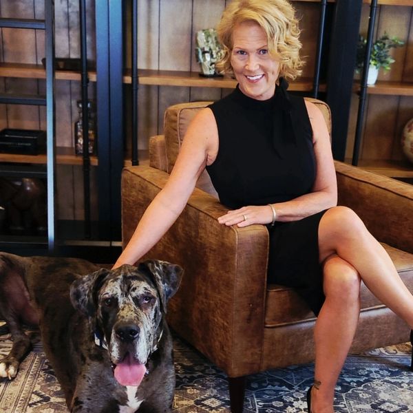Woman sitting on chair with large dog beside her.