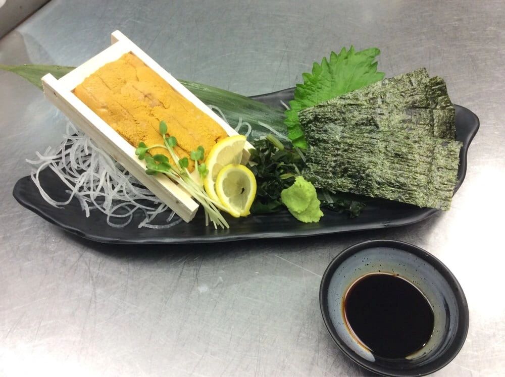 A plate of rice, sea weed sheets, soy sauce and leafy vegetable