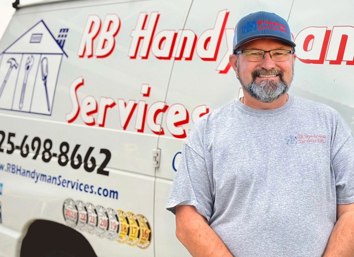 Smiling handyman in front of RB Handyman Services van.